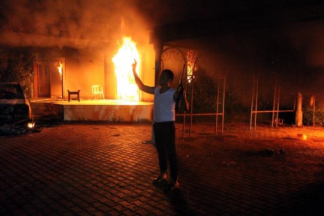 A man holds a gun in the air next to burning buildings at the U.S. consulate in Benghazi on Sept. 11, 2012. Libyan officials  said Thursday an American teacher was shot and killed in the troubled city.